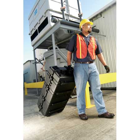 A construction worker is moving a Pelican 1770 Transport case on its wheels.