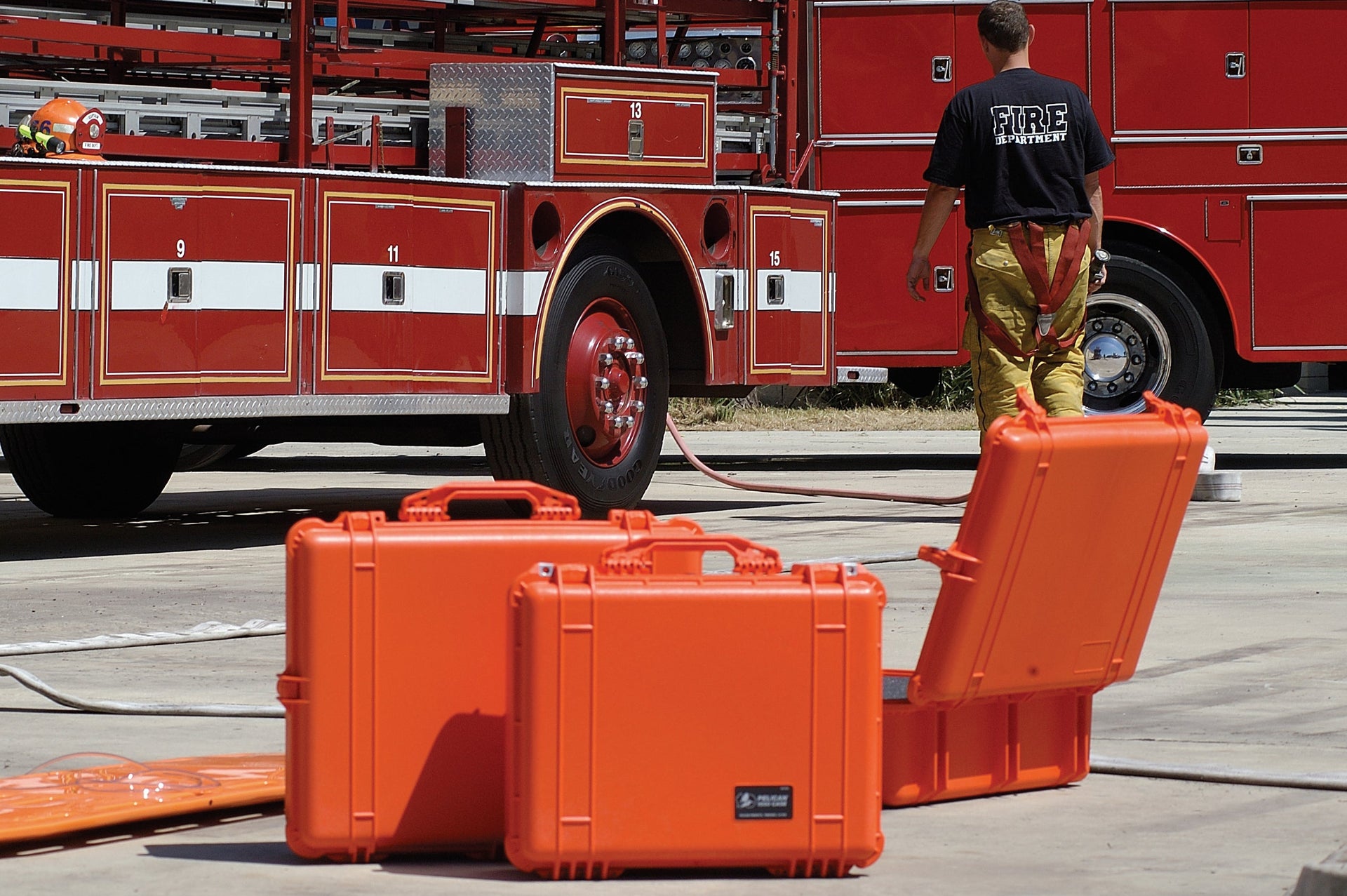 Orange protective cases on a concrete surface with a red fire truck in the background.
