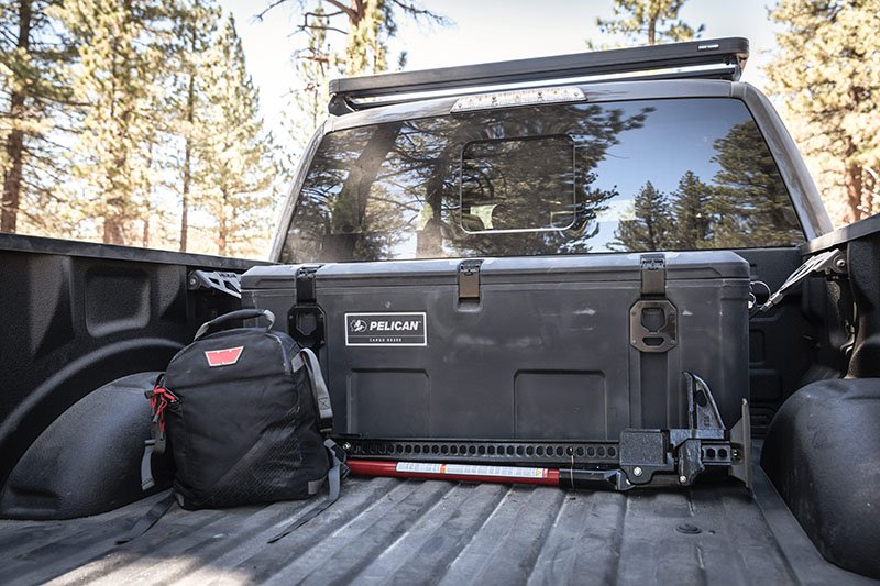 Load image into Gallery viewer, A black Pelican cargo BX255 case in a truck bed with gear around it.
