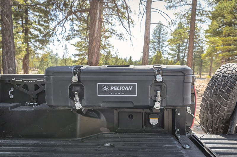 Load image into Gallery viewer, A black Pelican BX55S case attached to the interior side of a truck bed. The truck is in the forest.
