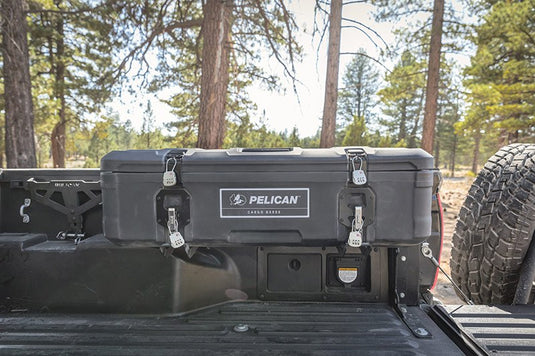 A black Pelican BX55S case attached to the interior side of a truck bed. The truck is in the forest.