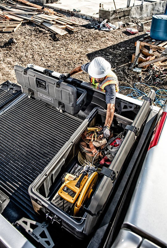 Load image into Gallery viewer, A Pelican Cargo BX255 case sitting open in a truck bed with construction tools inside. A Pelican Cargo BX55S is sitting open next to it. A construction worker is grabbing a tool from the BX255.
