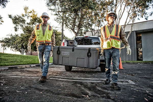 Two construction workers are carrying a Pelican Cargo BX255 case.